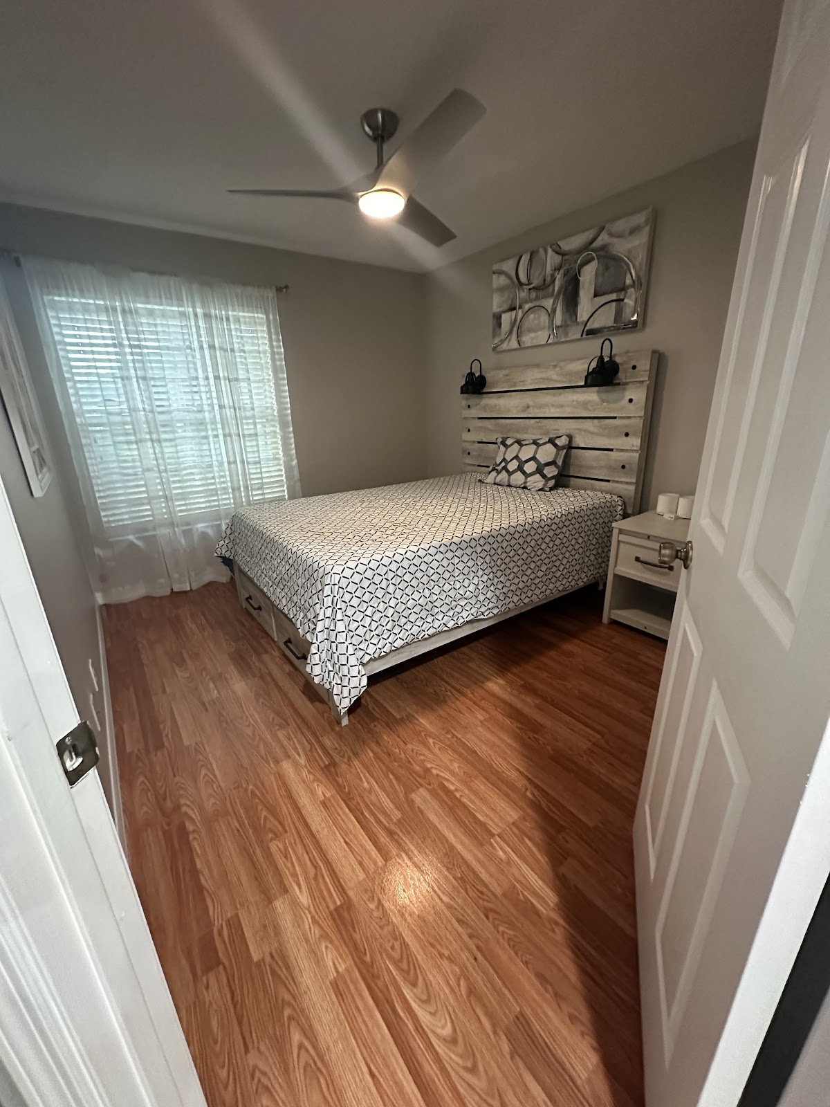 Neatly made bed and wood flooring in a home from the business gallery