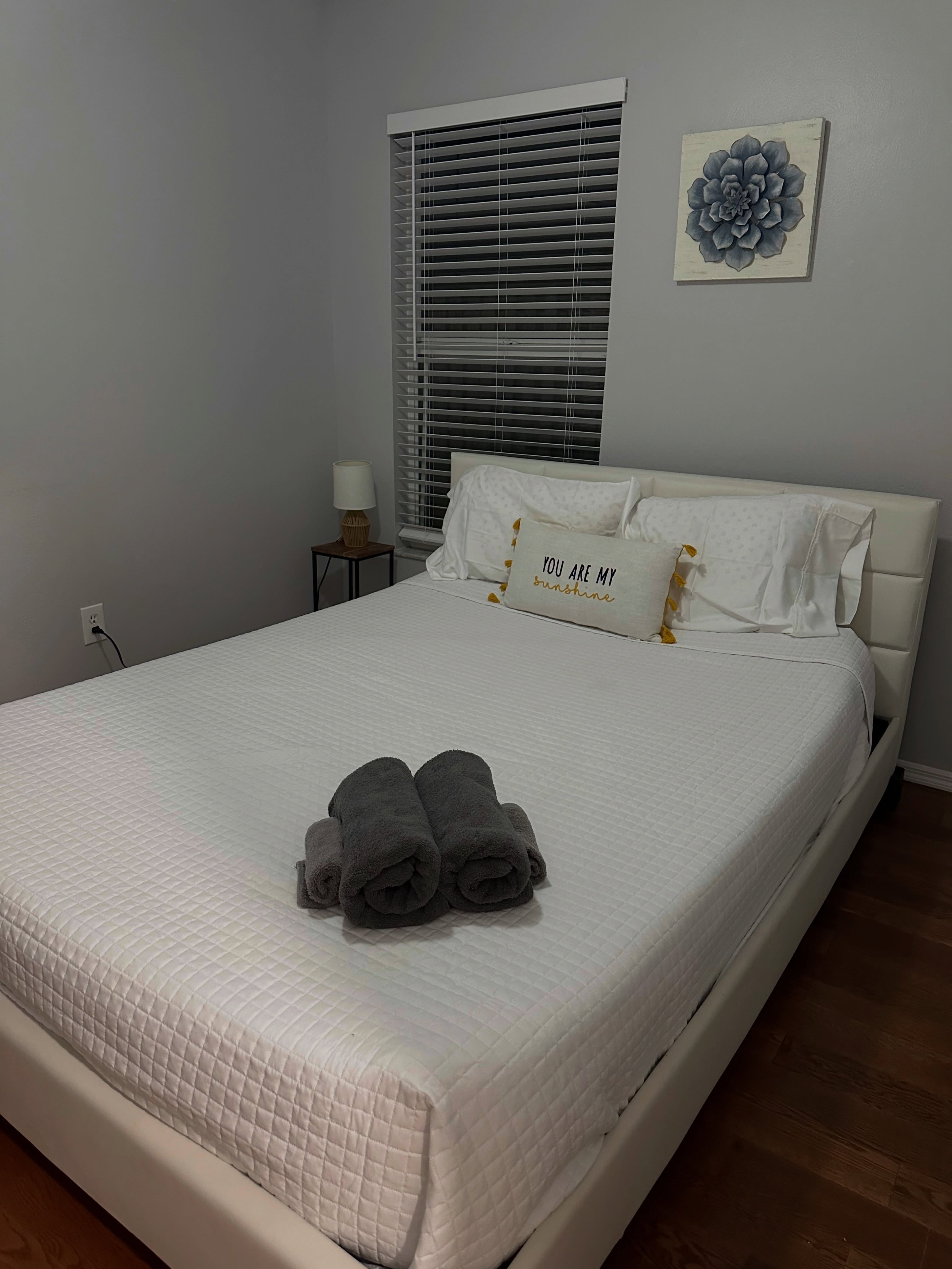 Made bed with white bedding and rolled gray towels